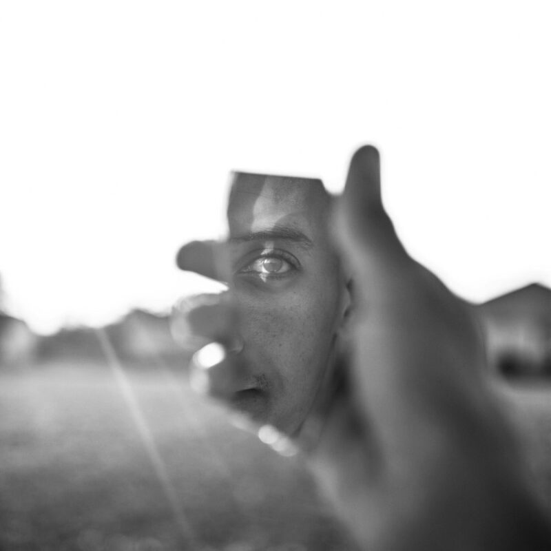 Person looking at reflection in broken piece of mirror