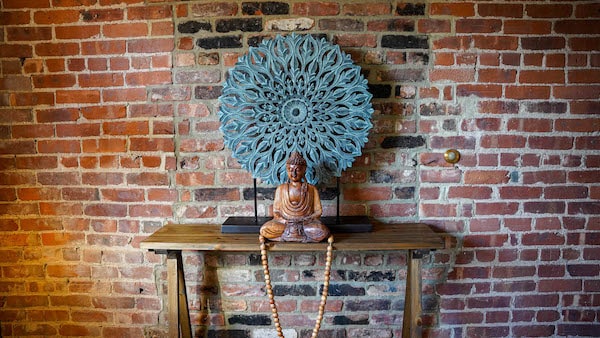 Buddha statue in front of brick wall