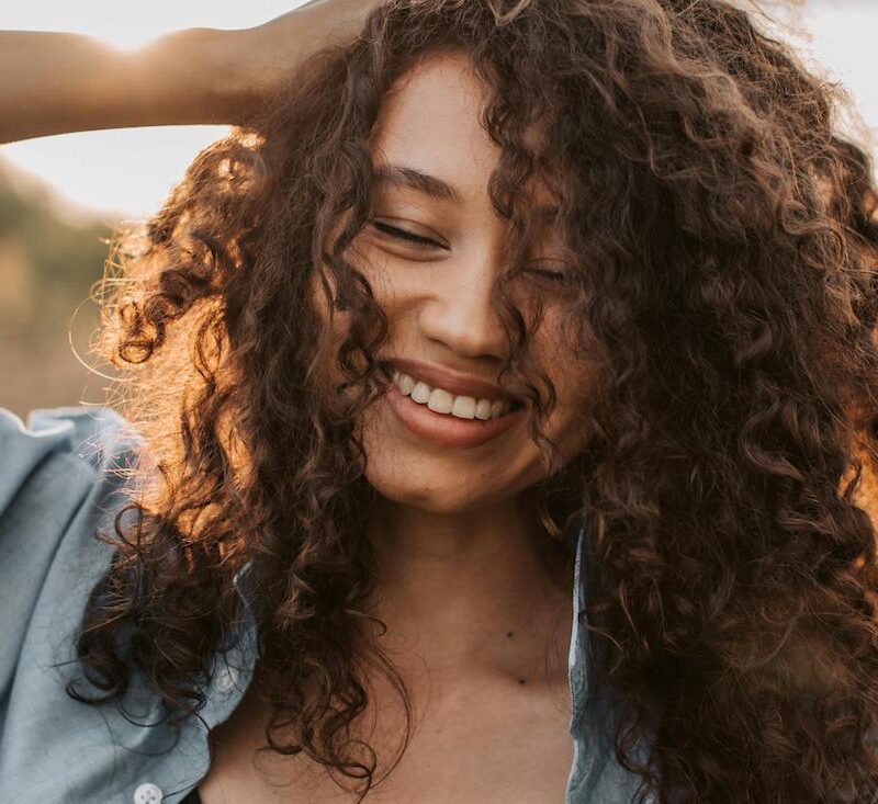 woman with hand on head smiling