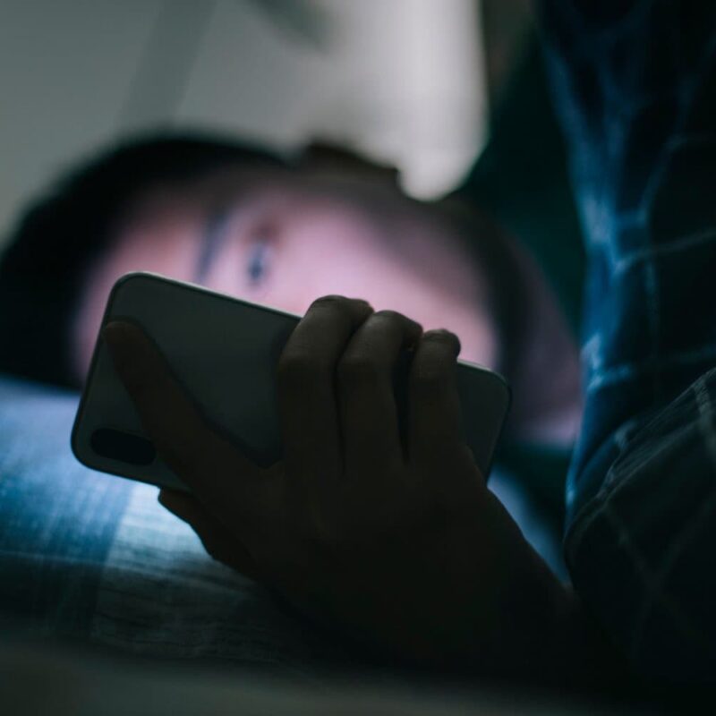 person looking at phone while in bed