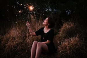 woman-holding-sparkler-while-sitting-down
