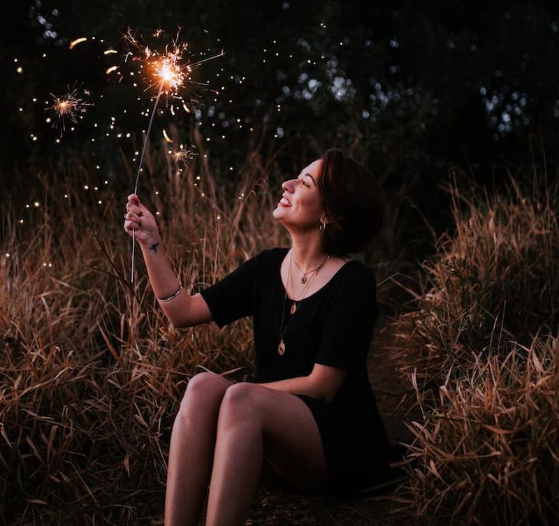 woman-holding-sparkler-while-sitting-down