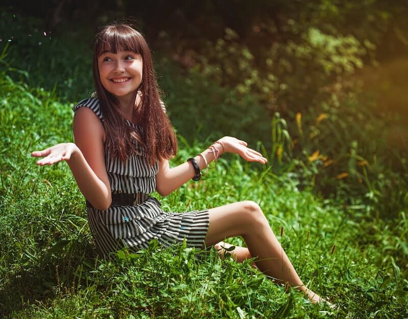 girl-sitting-on-grass-in-summer-and-smiling