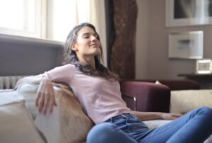 photo-of-woman-in-pink-long-sleeve-shirt-and-blue-denim-jeans-sitting-on-brown-sofa-with-her-eyes-closed