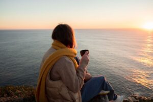 a-woman-sitting-near-the-cliff-holding-a-mug